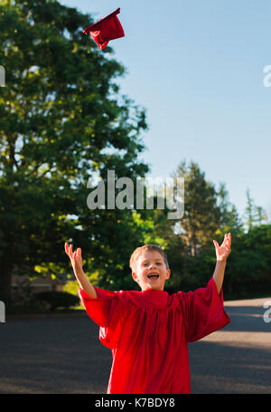 Portrait von Happy Boy an der Staffelung Kleid werfen mortarboard auf Fußweg Stockfoto