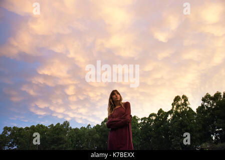 Junge Frau draußen in der Dämmerung, in Gedanken Stockfoto