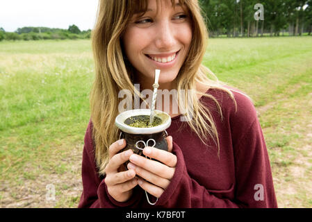 Junge Frau trinkt Mate in Kürbis Stockfoto