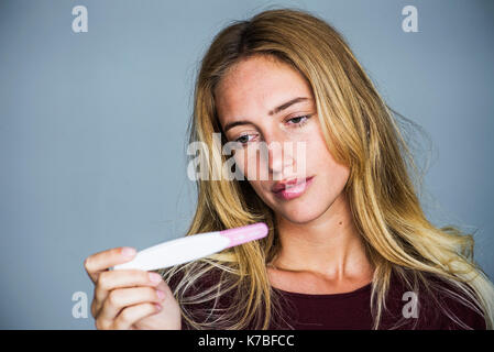 Junge Frau von der Schwangerschaft Test mit enttäuscht Ausdruck suchen Stockfoto