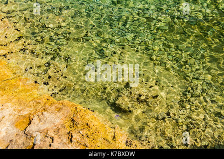 Felsige Meeresboden durch kristallklaren türkis transparent Plätschern des Wassers sichtbar. Stockfoto