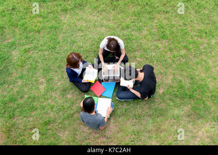 Blick von oben auf die Gruppe der asiatischen Studenten zusammen im Park sitzen. Studenten tun group study. Stockfoto