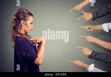 Beschuldigen Sie. In dem Bestreben, wütende Frau, die von verschiedenen Personen Pointing Finger Hände an ihr gerichtet. Negative menschliche Emotionen Gesichtsausdruck Gefühl Stockfoto