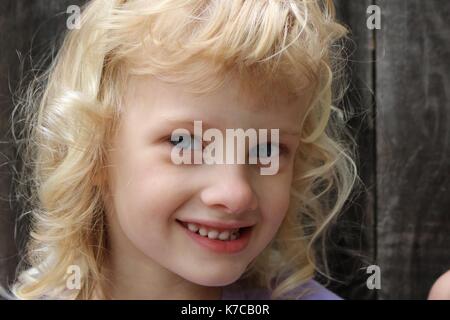 Nahaufnahme, Porträt einer jungen blonden Mädchen mit einem verschmitzten Lächeln Stockfoto