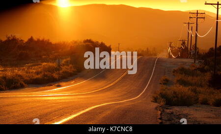 Curvy Wüste Autobahn Straße gehen, dachte der südlichen Kalifornien Golden State bei Sonnenuntergang mit einer Telefonleitung funkeln mit Gold Stockfoto