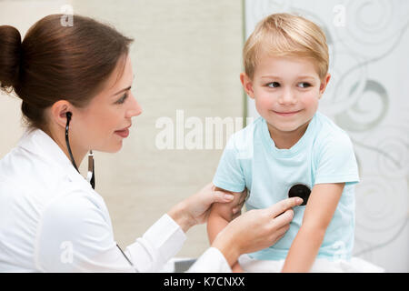 Happy little boy am Doktor tapfere, junge weibliche Kinderarzt mit Stethoskop hören Babys Lungen, Besuche bei Arzt Stockfoto