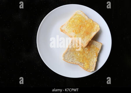 Brot mit Marmelade Ananas in Weiß Teller auf der Tabelle platziert. Stockfoto