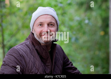 Stattliche reifer Mann lächelnd in warme Mütze und Jacke an Kamera Stockfoto