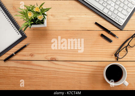 Büro Schreibtisch Tisch mit Tastatur, Notebook, Kugelschreiber, Tasse Kaffee und Blume. Ansicht von oben mit der Kopie Raum (selektive Fokus) Stockfoto