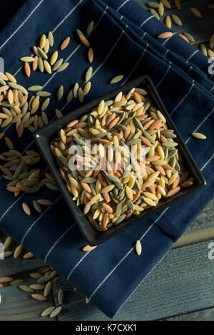 Trockene organische Tricolor Orzo Pasta in eine Schüssel geben. Stockfoto