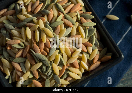 Trockene organische Tricolor Orzo Pasta in eine Schüssel geben. Stockfoto