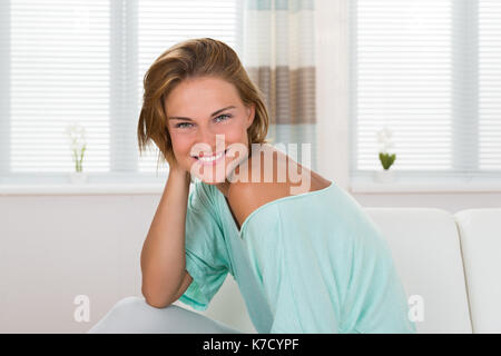 Porträt der jungen Frau sitzt auf einem Sofa Stockfoto