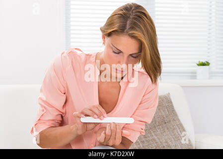 Porträt der jungen Frau Feilen Nägel mit Nagelfeile zu Hause Stockfoto