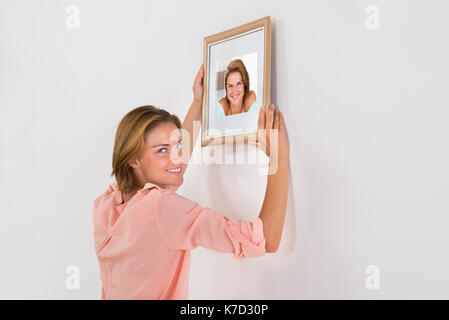 Schöne glückliche Frau, Bilderrahmen an der Wand des Hauses Stockfoto