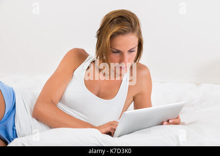 Junge schöne Frau im Bett mit digitalen Tablet Stockfoto