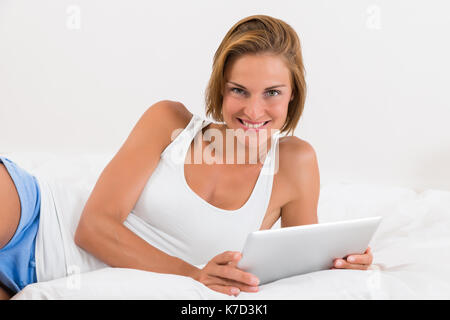Junge schöne Frau im Bett mit digitalen Tablet Stockfoto