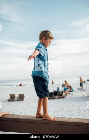 Junge mit ausgestreckten Armen zu Fuß auf Holzbrett in Panama City Beach gegen Sky Stockfoto