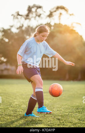 Mädchen kicken Fußball beim Spielen an Feld Stockfoto