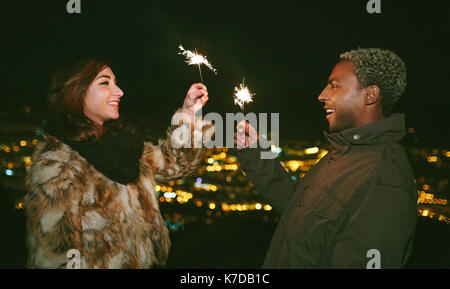 Glückliches junges Paar ständigen Gesicht zu halten Wunderkerzen während der Nacht Stockfoto