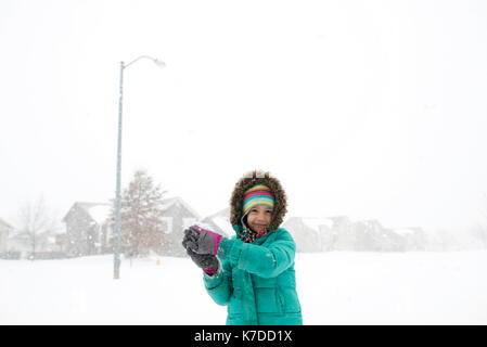 Portrait von glücklichen Mädchen in warme Kleidung spielen mit schneeball Stockfoto