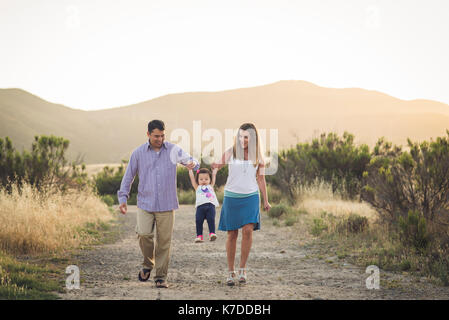 Glückliche Eltern heben Tochter beim Gehen auf gegen den klaren Himmel Stockfoto