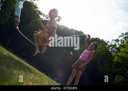 Mutter und Töchter spielen mit Seil springen im Park im Sommer Stockfoto