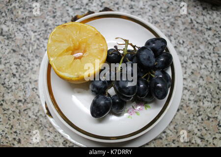 Frisch süß und saftig blaue Trauben mit einer halben Zitrone für Kleine Pause mit Mittagessen Stockfoto