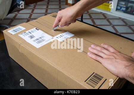 Auslieferung auspacken. Hände öffnen einen Versandkarton Stockfoto