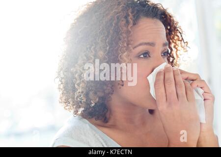 Mitte der erwachsenen Frau blasen Nase auf Gewebe. Stockfoto