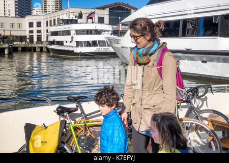 Familie auf einem Berkeley Fähre in San Francisco eintrifft. Mutter mit kleinen Kindern bereitet aussteigen. San Francisco Boote und Gebäude im Hintergrund. Stockfoto