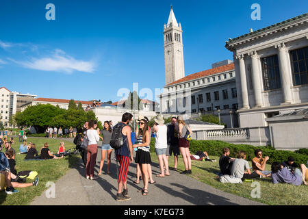 Studenten an der Universität von Kalifornien Berkeley Campus mit einem warmen Frühling Tag draußen auf dem Rasen. Das Campanile Turm im Hintergrund Stockfoto