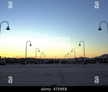 Sonnenuntergang gesehen von Jetty in Coffs Harbour, Urlaub, Australien. Im Blick sind Straßenlaternen, Holzbänke, Metall Geländer Stockfoto