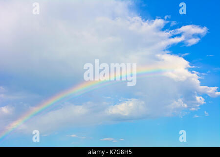 Regenbogen unter der weißen Wolke auf dem azurblauen Himmel. Stockfoto