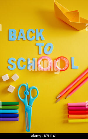 Zurück in der Schule versorgt und Buchstaben auf gelbem Hintergrund. Handwerk Stockfoto