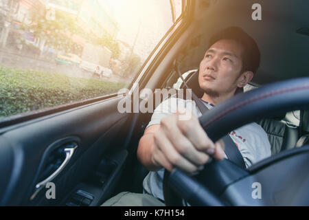 Asiatischer Mann Mann ein Auto fahren und Suchen an den Fenstern. Stockfoto