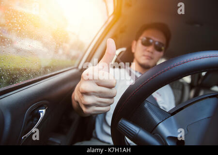 Gute Fahrt "Daumen hoch"-Konzept. Asiatischer Mann männliche Ware sun Glas ein Auto fahren. Stockfoto