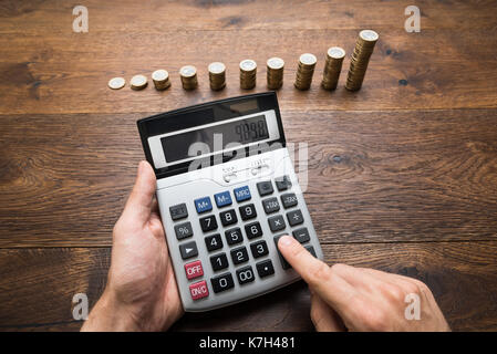 Geschäftsmann Berechnungen Vor gestapelte Münzen Stockfoto