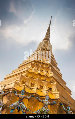 Wunderschöne verzierte Golden Chedi mit mythischen Dämonenwächtern um die Basis. Wat Phra Kaew (Tempel des Smaragd-Buddha), der große Palast, Thailand Stockfoto