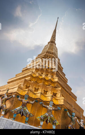 Wunderschöne verzierte Golden Chedi mit mythischen Dämonenwächtern um die Basis. Wat Phra Kaew (Tempel des Smaragd-Buddha), der große Palast, Thailand Stockfoto