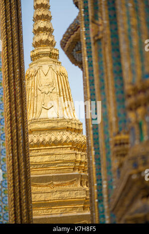 Wunderschöne verzierte Golden Chedi durch die kleine Lücke zwischen Phra Mondop und Prasat Phra Dhepbidorn im Wat Phra Kaew gesehen. Der Große Palast, Thailand Stockfoto