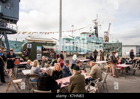 England, Chatham Dockyard, Gruß an die 1940er Veranstaltung. Menschen, viele in Kostümen und einheitliche, Sitzen im Freien Tische und Sitzgelegenheiten mit NAAFI Stil van mit Kaffee, Tee und Snacks. Stockfoto
