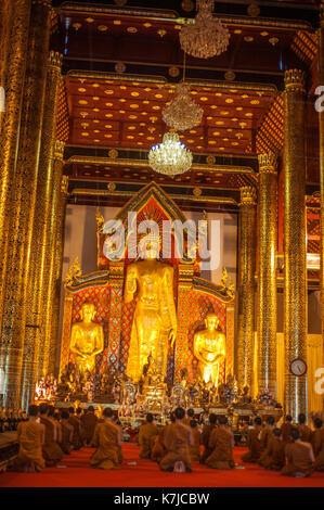 Mönche knien vor Buddha Statuen in den Wat Chedi Luang Tempel in Chiang Mai, Thailand Stockfoto