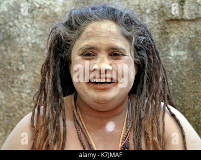 Die indische Hindu-Frau Sadhu (Sadhvi) mit langen Dreadlocks und einem feierlichen weißen Makeup aus heiligem Eschen (Vibhuti) lächelt für die Kamera. Stockfoto