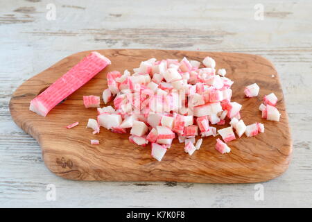 Crab Sticks auf einem olivenholz Schneidebrett schneiden. Schritt für Schritt das Kochen. Stockfoto