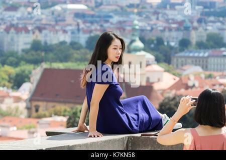 Prag, Tschechische Republik - 19 August 2017: Asiatische Mädchen sitzen auf die Wand von einem Balkon mit Panoramablick auf die Stadt. Stockfoto