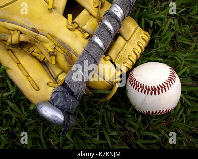 Foto eines Baseball Handschuhe, Baseball und einem Baseballschläger auf dem Gras Stockfoto