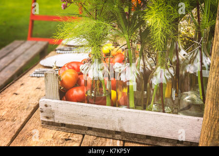 Holz- table Setup für das Abendessen mit Vase Flaschen und frische Tomaten. Stockfoto