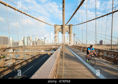 Brooklyn Bridge an einem sonnigen Morgen mit man radfahren in New York. Es ist eine alte Brücke im Jahr 1883 abgeschlossen. Stockfoto