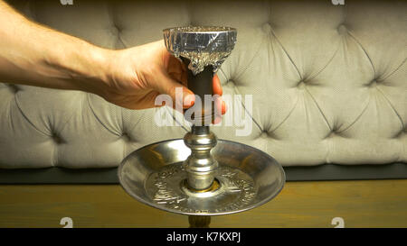 Rauch Shisha auf einem schwarzen Hintergrund mit einem schönen Rauch. Braun shisha Schüssel für Tabak mit langem Bein. Vorbereiten der Shisha, nargile Shisha aka oder in einem Restaurant, indem Sie den Holzkohlen auf der Oberseite. Stockfoto