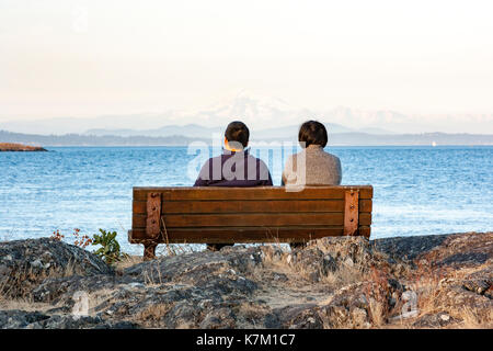 Pärchen auf Parkbank am Cattle Point, Uplands Park, Oak Bay, Victoria, Vancouver Island, British Columbia, Kanada Stockfoto